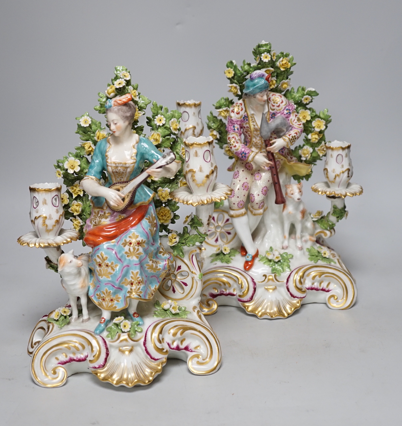 A pair of French porcelain two branch figural candlesticks in the form of musicians, largest 29cm high